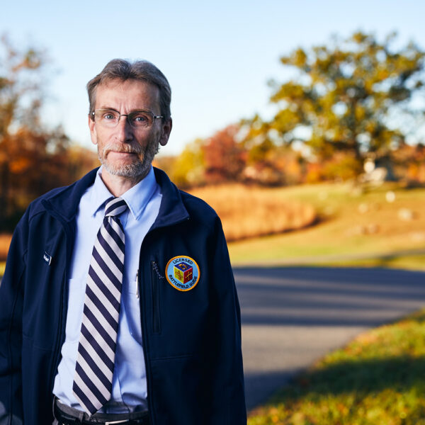Man wearing glasses and a navy blue Licensed Battlefield Guide jacket.
