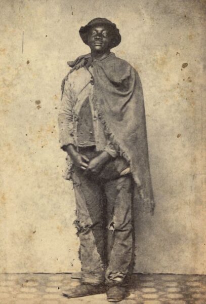 William Headly, who escaped slavery from plantation near Raleigh, North Carolina, in a photo taken shortly after he reached Union lines. A photographer's note says that Headly's "clothes were of many colors and qualities ... [and his] cloak consisted of an old cotton grain bag, slit open on one side."
