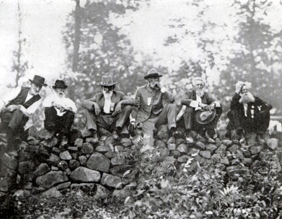 Gettysburg veterans sit on a rock wall.