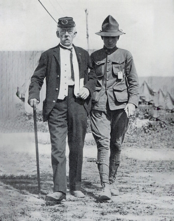 A Boy Scout escorts a veteran through camp.