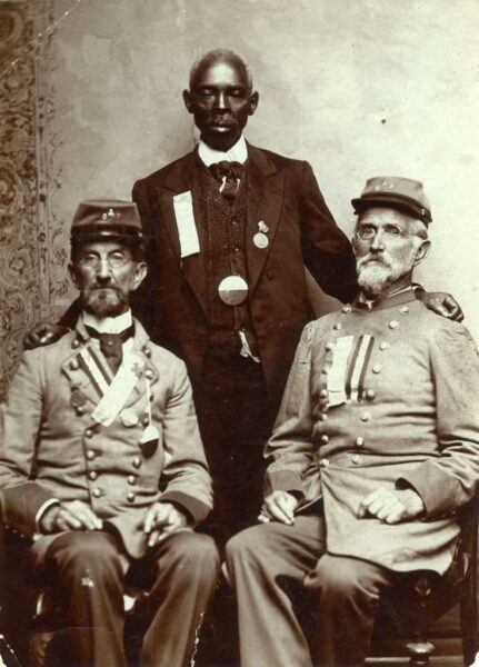 Two Confederate veterans pose with a black man—presumably a former body servant—in a postwar image.