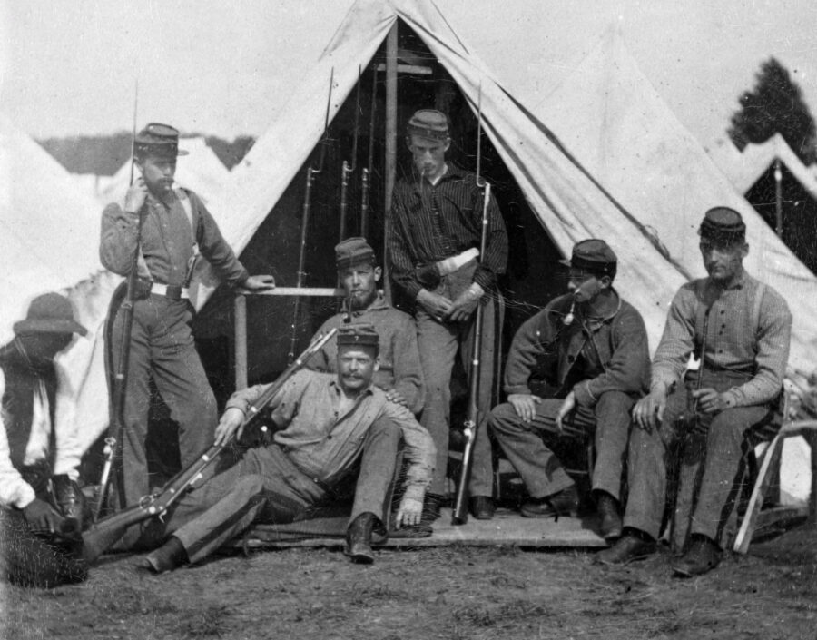Civil War soldiers relaxing in front of a tent.