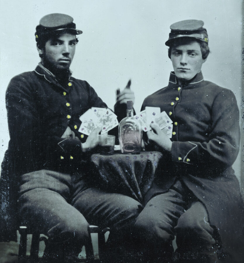 Union soldiers play cards with a bottle of liquor between the two of them.