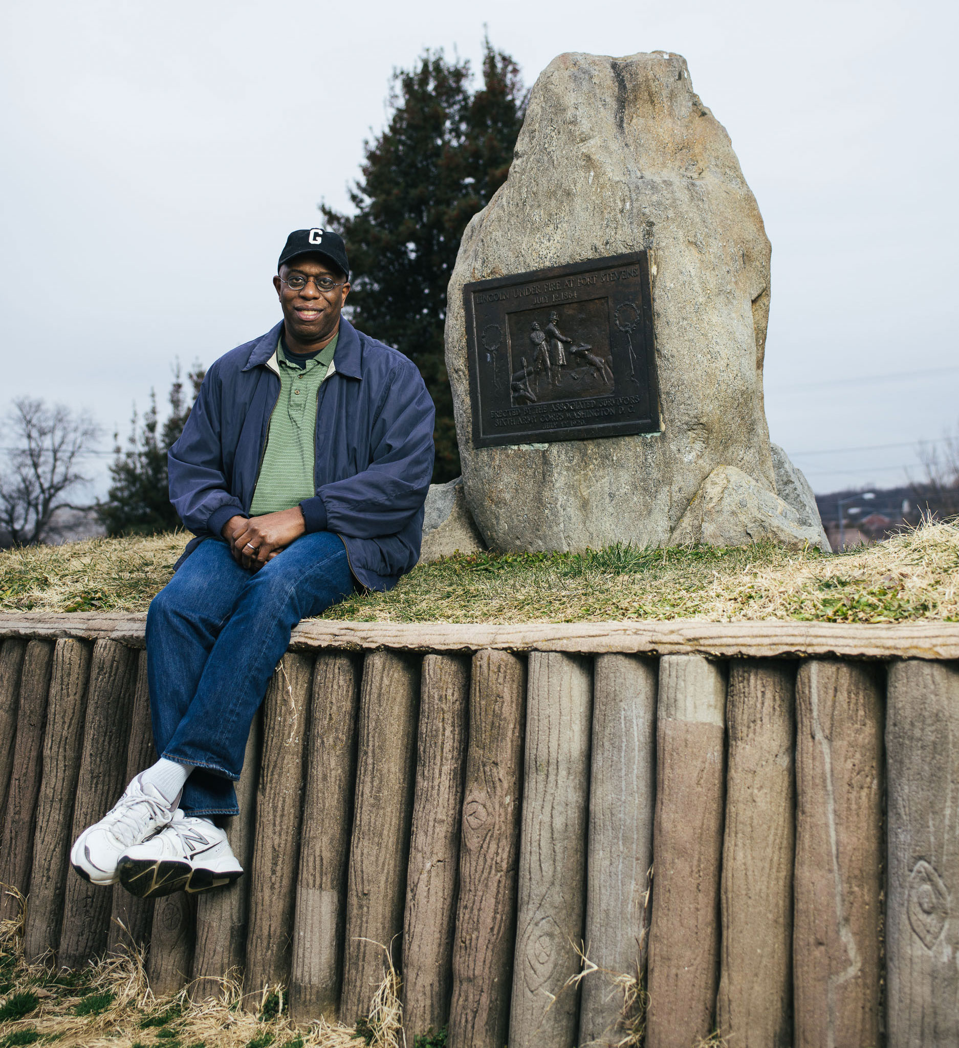 Man sits next to a monument at a Civil War battlefield.