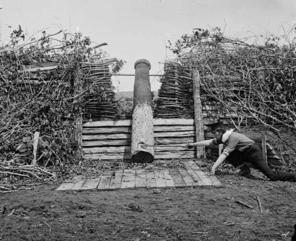 A man pretends to fire a faux cannon devised from a wooden log, or Quaker gun, found in abandoned Confederate defensive works.