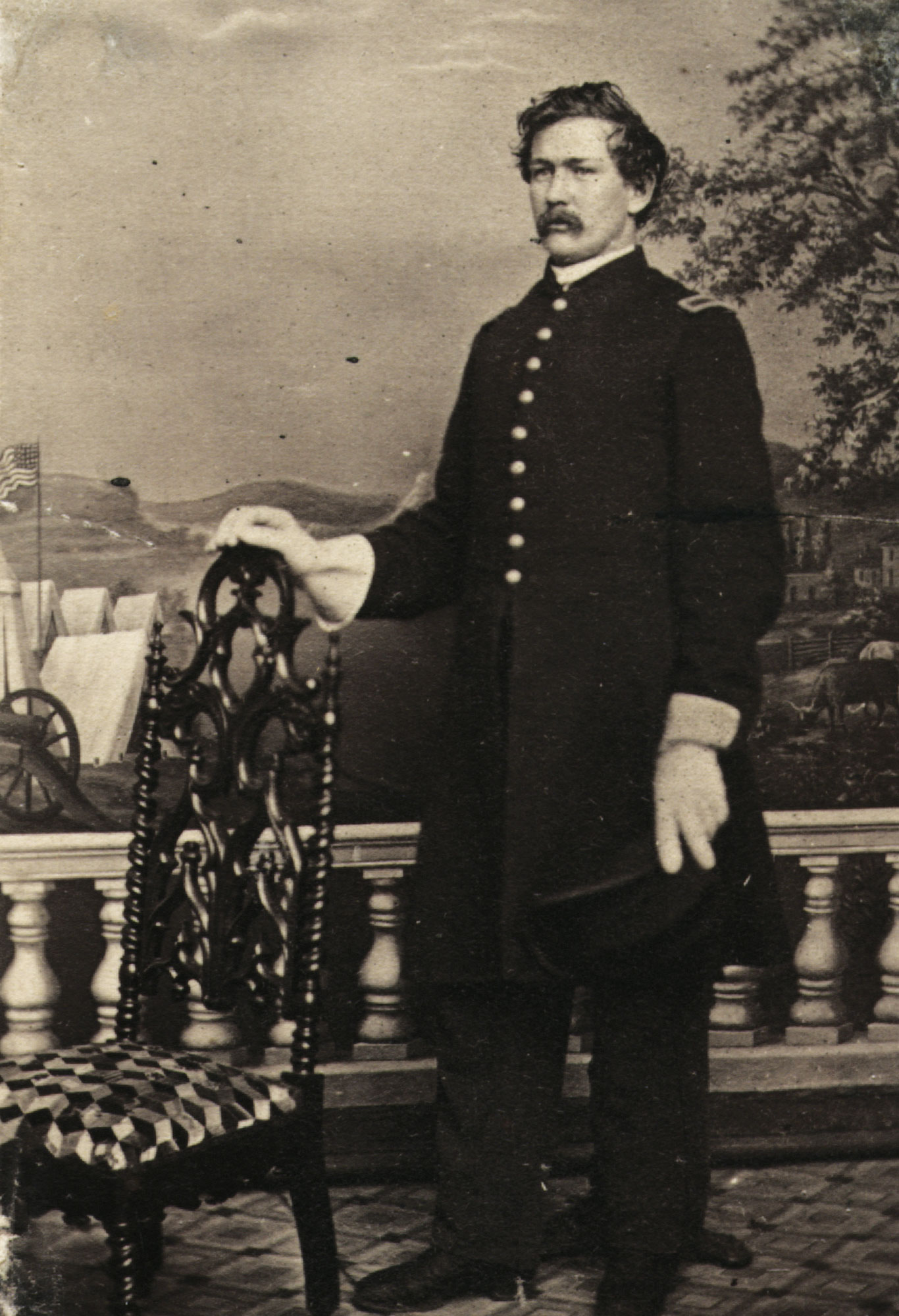 Portrait of a Civil War soldier standing next to a chair.