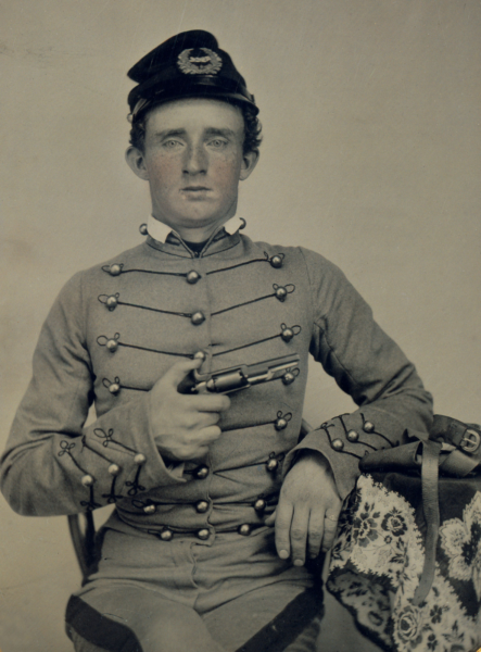 Young George Armstrong Custer seated in West Point uniform holding a pistol, circa 1860
