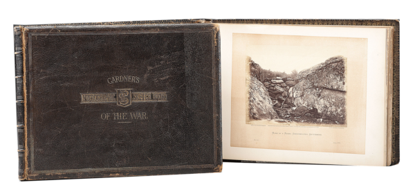 Two volumes of Gardner's Photographic Sketch Book of the War, showing the leather cover and an open page with a Civil War photograph.