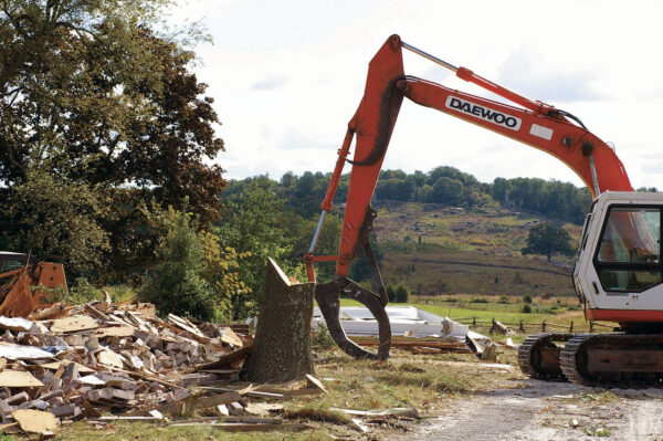 A large excavator demolishes modern structures on the Snyder Farm Tract at Gettysburg.