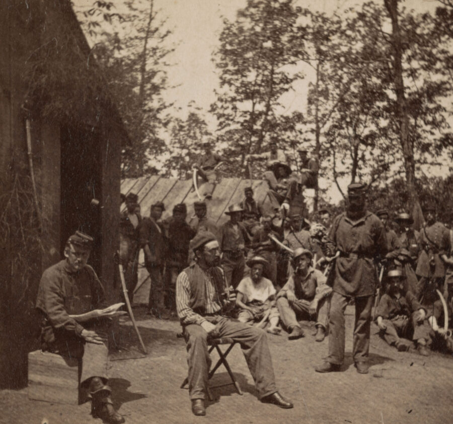 Civil War soldiers reading at camp.
